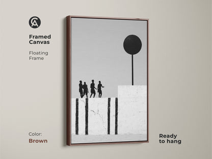 Framed canvas in a brown frame showcasing surreal figures. Monochrome art with a black sphere accents the minimalist home decor look. This abstract figure silhouette print adds an artistic touch to any space. Ready to hang.
