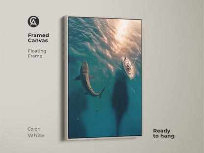 Framed canvas art of a great white shark and sailboat. White floating frame emphasizes this modern ocean art. Ready to hang this blue ocean wall hanging adds a coastal adventure theme. Ideal for shark lover gifts.