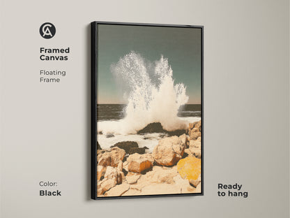 Framed canvas in black featuring teal ocean wave art. This coastal seascape wall art captures a crashing wave on a rocky shore. It is ready to hang in any room. The beach house canvas art adds coastal living charm offering serene power.