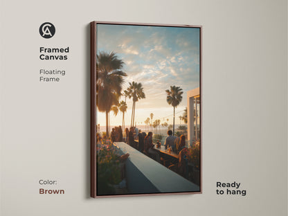 Framed canvas art with a brown floating frame. The artwork captures a sunset from a rooftop bar. It features palm trees and people enjoying the view. It is ready to hang. This piece will bring warmth to your home decor.