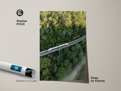 Poster print of an aerial train in a green forest. This modern transportation print is easy to frame. The rolled canvas showcases nature landscape art. This green nature photography is perfect for office wall decor. It's a unique wall hanging for travel enthusiasts.