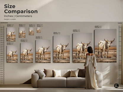 A size comparison displays cream and brown bull artwork in inches and centimeters. A model stands next to the canvas wall art. The rustic cow wall decor is shown above a couch. Choose the perfect piece of farmhouse animal wall art. It's a great housewarming rustic gift.