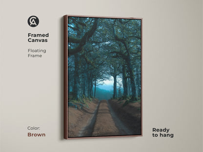 A framed canvas with a floating frame presents a tree tunnel in emerald hues. This dark academia landscape artwork is ready to hang. The brown frame complements the natural landscape wall decor beautifully.