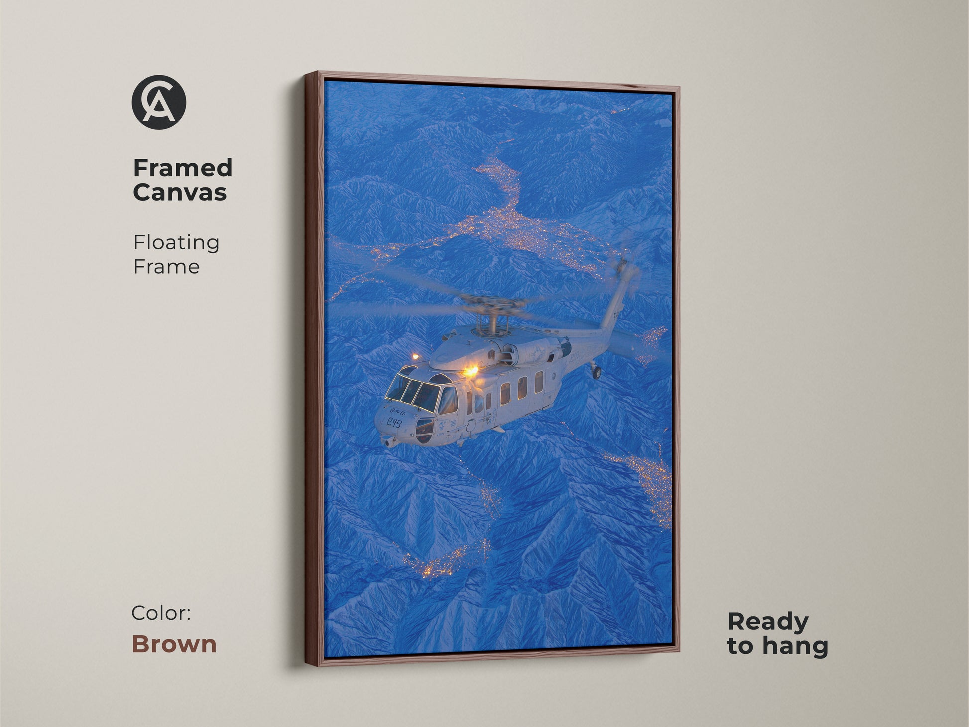 A helicopter is featured over a city nestled in the mountains in this framed canvas artwork. The brown floating frame complements the image's cool tones. This ready-to-hang aviation art adds a touch of adventure to your decor.