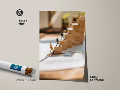 This is a poster print of miniature figures climbing wooden blocks. This conceptual business print is easy to frame. The art piece is motivational decor for offices. It shows teamwork and goals. This artwork is rolled in a tube for convenient shipping.