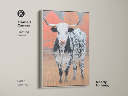 Enhance your decor with framed Longhorn Cow art. The floating frame is white. The art features a black and white speckled Longhorn in a field. Autumn trees provide a backdrop. It is ready to hang