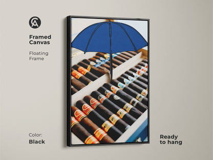 Black framed canvas featuring a surreal cigar box and blue umbrella artwork. Ready to hang art adds sophistication. A great masculine wall decor for an office. The floating frame enhances the premium art print. The perfect gift for cigar lovers who appreciate fine art.