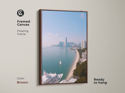 A framed canvas showing coastal cityscape art with a yacht and sailboat. This floating frame artwork is ready to hang and features a brown frame. The ocean view art print features modern aqua blue artwork. It is a contemporary cityscape print perfect for travel lovers. The coastal scene offers nautical themed wall decor.