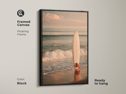 Black framed canvas art showing a surfboard on the beach. The floating frame enhances the artwork. It is ready to hang. This piece brings a touch of coastal charm to your home. Perfect for ocean lovers.