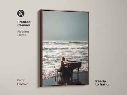 Framed canvas art with a brown floating frame. The artwork depicts a woman playing a piano on a serene beach. This piece is ready to hang. Its warm tones complement any room. Bring the calm of the ocean into your decor with this framed art.