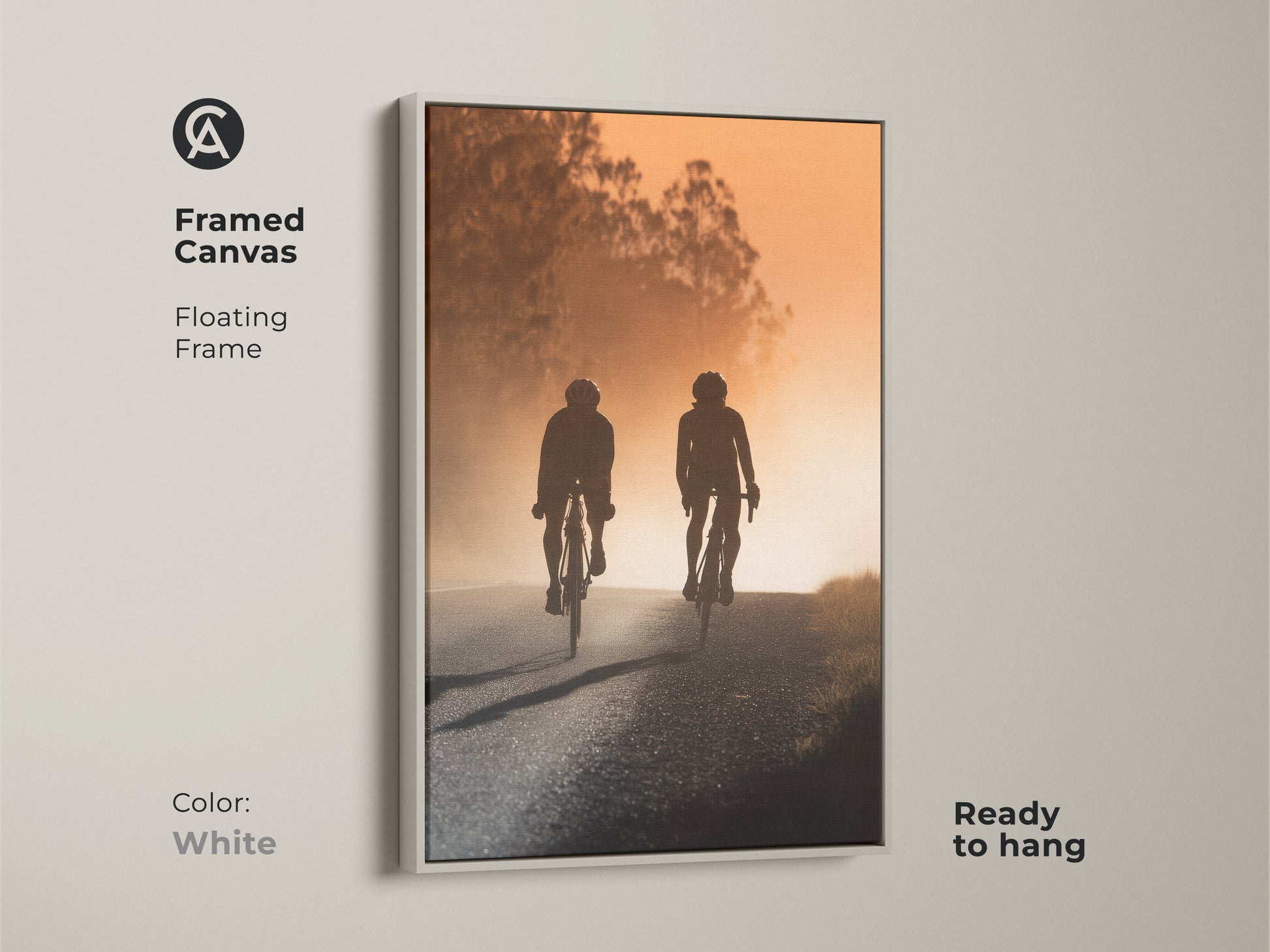 Framed canvas art with a road cyclist silhouette. The artwork has a white floating frame. It shows a warm amber sunset landscape. Ready to hang this modern sport art.