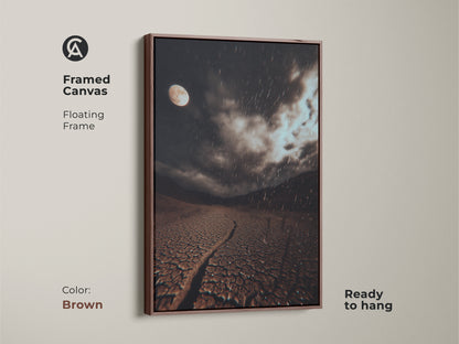 Brown framed canvas art featuring a surreal moonlit desert landscape. This dark brown cracked earth art has a grey rainy night sky. It's ready to hang. A great gift for stargazers.