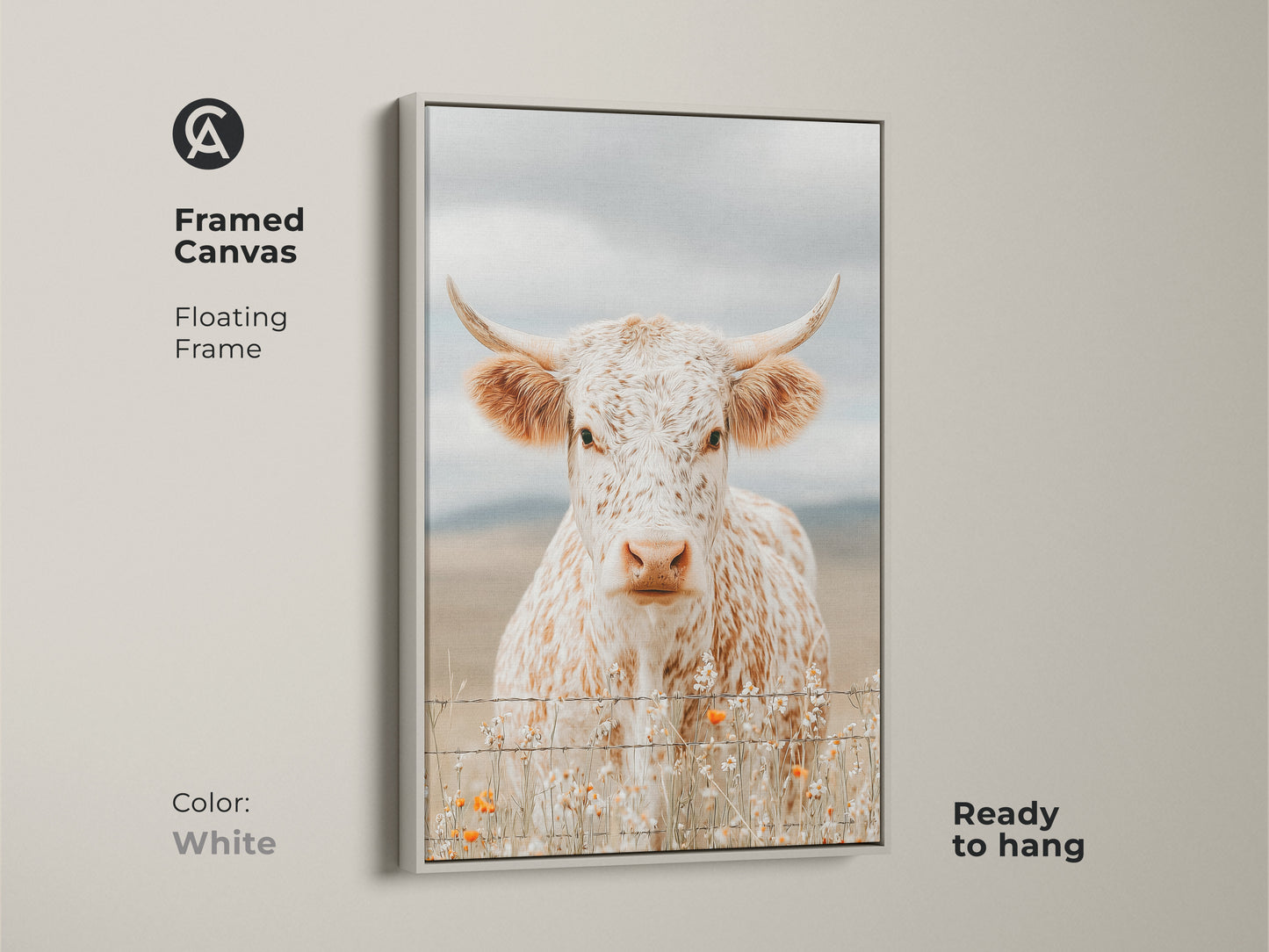 Framed canvas artwork of a white and brown speckled longhorn cow in a white floating frame. The cow is standing behind a barbed wire fence. Orange wildflowers grow at the base. This framed art is ready to hang now.