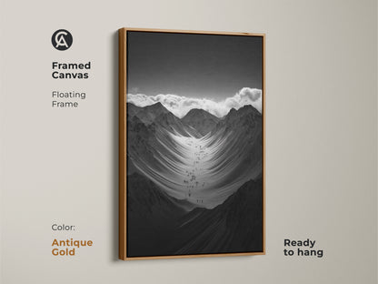 Framed black and white mountain art print with a antique gold floating frame. This monochrome canvas art is ready to hang. The hikers are ascending a vast snowy mountain range. This nature scenery wall art adds adventure to any space.