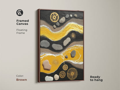 Brown framed canvas displaying yellow and black abstract artwork. This textured home decor piece is ready to hang. It has pebble and gear accents. This contemporary art print is perfect for design lovers.