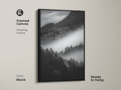 Black framed canvas of a monochrome mountain landscape. This foggy village print showcases black and white nature canvas art. The contemporary wall decor is ready to hang. A minimalist home art piece with a floating frame.