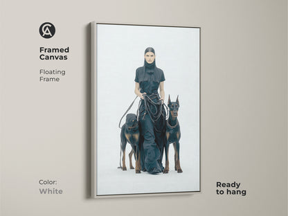 Framed canvas print of woman with Dobermans with a white floating frame. Ready to hang. Monochrome minimalist artwork for contemporary home decor. Ideal for dog lovers. High-contrast black and white fashion art.