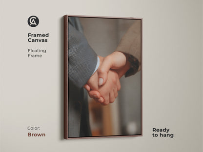 Framed handshake canvas art with a floating brown frame. Ready to hang. This business partnership artwork promotes corporate success. Ideal for modern office decor. A professional gift option. Neutral color palette complements any workplace. Symbolizes teamwork.