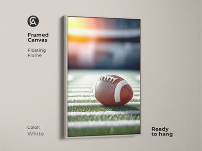 White framed canvas featuring a realistic football on a stadium field. The floating frame is white. This game day football decor is ready to hang. Perfect sports fan wall decor. A great piece for a man cave sports art.