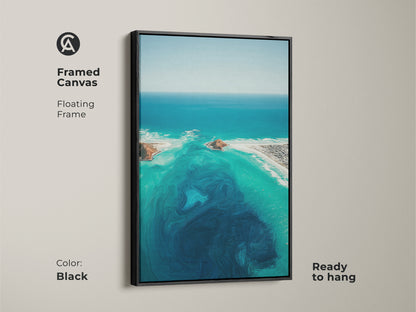 Black framed canvas of an abstract ocean. This turquoise aerial view artwork is coastal landscape wall art. It displays deep blue swirls and aqua beach house decor. The floating frame is ready to hang.