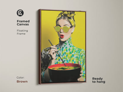 Framed canvas with a brown floating frame displaying a pop art woman enjoying noodles. This retro-style artwork is ready to hang. The vibrant yellow and teal colors make it a unique kitchen art piece. Perfect for foodie fashion.