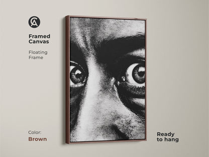 Framed canvas of a monochrome face portrait with a brown floating frame. Ready to hang this intense gaze canvas art adds a contemporary touch. The expressive eyes artwork is perfect for modern monochrome decor. Enhance your entryway with this bold black and white print.