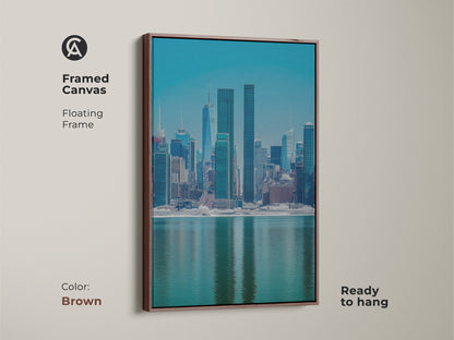 Framed canvas displaying a modern NYC skyline in blue and teal. The brown floating frame complements the contemporary cityscape artwork. This urban waterfront view print is ready to hang. Ideal for living room wall art or office decor.