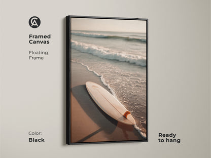 Black framed canvas art featuring a surfboard on the beach. The floating frame enhances the artwork's visual appeal. Ready to hang this black framed art adds sophistication to any room. A perfect piece for modern coastal decor. Bring the beach home with this elegant art.