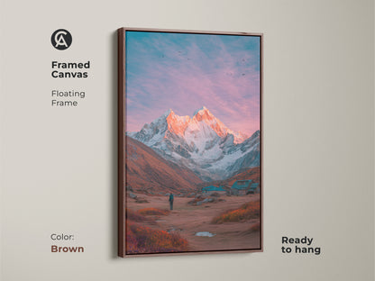 Brown framed canvas art featuring a mountain vista. A hiker admires the snow-capped mountain. The floating frame enhances the artwork's beauty. Ready to hang. This mountain artwork brings the outdoors inside. Perfect home decor.
