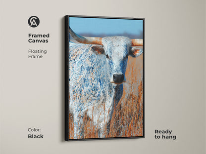This framed canvas art features a longhorn bull. The artwork has a floating frame. The frame color is black. This canvas print is ready to hang. The animal art is a beautiful addition to any space.