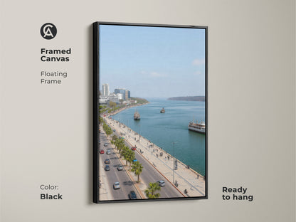 Framed canvas artwork featuring a blue teal coastal cityscape. The black floating frame enhances the travel photography. Palm trees line the street. Perfect for entry hall decor. Contemporary seaside art.