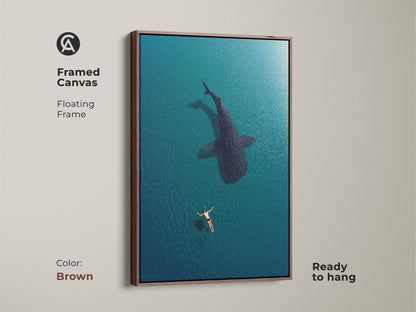 Brown framed canvas featuring aerial ocean art of a swimmer and whale shark. This ready-to-hang coastal artwork brings a warm touch to your home. The deep blue turquoise tones create a calming underwater scene perfect for any beach house or nautical decor.