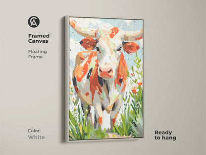 A white framed canvas displays longhorn cow artwork. The floating frame gives a modern touch. The artwork combines orange white and cream tones. Green accents add life. This canvas is ready to hang.