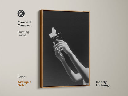 Framed monochrome insect art featuring surreal hands reaching for a butterfly. This minimalist black and white art is ready to hang. The antique gold frame offers an elegant touch. This fine art canvas print is a perfect gift for artists. It is ideal for a bedroom or any modern space.