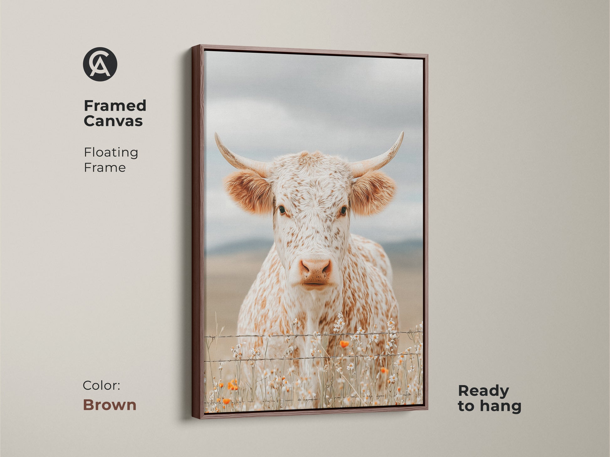 Framed canvas artwork of a white and brown speckled longhorn cow in a brown floating frame. The cow is standing behind a barbed wire fence. Small orange wildflowers grow at the base. This framed art is ready to hang.