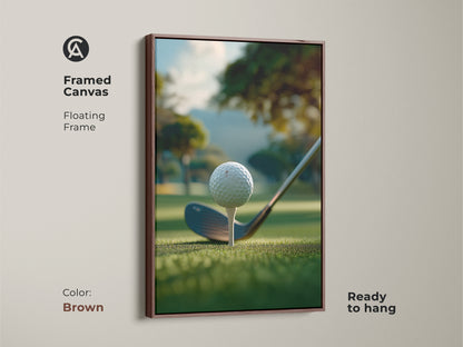 A brown framed canvas golf art print ready to hang. The artwork shows a golf ball on a tee ready to be hit. The background is a green golf course with trees and a hill. This framed golf art print is perfect for your home or office.