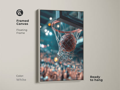 Framed canvas art in white featuring a basketball going through the net. This floating frame is ready to hang. The blurred crowd is in the background. This clean artwork adds a modern and sporty touch to any room. Show your love for basketball.