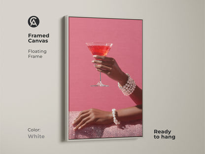 Brighten your space with this framed canvas of chic pink martini art. The white floating frame adds a fresh touch. The artwork features a hand with a pearl bracelet. It's a contemporary cocktail decor that's ready to hang. Ideal glam bar wall art for a modern look.