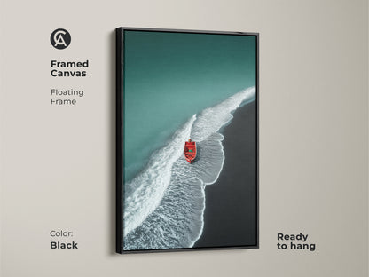 Framed canvas art with a floating black frame. This aerial beach artwork showcases teal waters and dark sand. A red boat adds a vibrant touch. Ready to hang nautical wall decor.