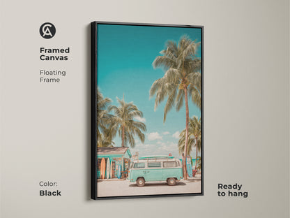 Framed canvas art capturing a light teal VW bus parked near a beach surf shop. The black floating frame complements the tropical palm trees and surfboards. This ready-to-hang artwork brings a refreshing summer vibe to your home.