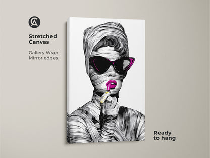 Close up of a Stretched Canvas Print. This surreal fashion wall art shows a pop art woman portrait. She is wrapped in mummy bandages and wears magenta lipstick. The gallery wrapped canvas with mirror edges is ready to hang. It's a unique wall art gift.
