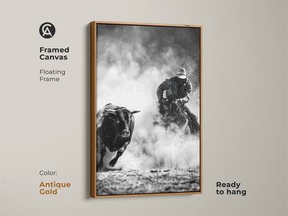 Framed canvas art shows a cowboy riding a bull. The Western action scene print is monochrome cowboy decor. This grayscale bull art is perfect for a man cave. Ready to hang with a floating frame in antique gold.