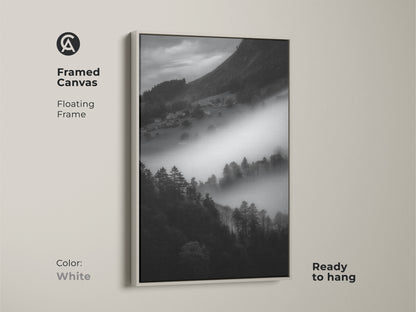 White framed canvas art of a monochrome mountain landscape. The foggy village print is black and white. Contemporary wall decor is ready to hang. The minimalist home art has a floating frame adding to its serene nature art.
