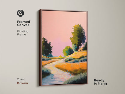 Brown framed canvas showcasing pink yellow and orange wall art. The expressive nature artwork with a boho river trees print is ready to hang. A countryside scenery artwork for nature lovers.