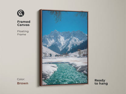 This framed canvas features a winter mountain landscape art with a brown floating frame. Ready to hang snowy river canvas print for rustic nature wall decor. A great gift idea for outdoor enthusiasts in a blue teal landscape painting.