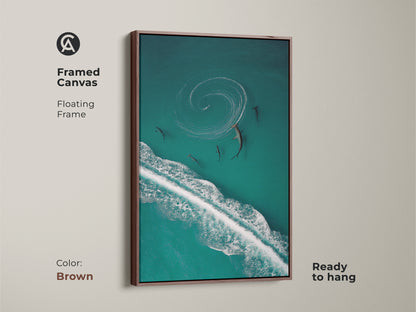 Enhance your home with this framed ocean wave canvas art. Showcasing sharks in turquoise waters this wildlife print adds coastal flair. Ready to hang and admire this unique artwork features a brown frame. A perfect piece for beach house decor.