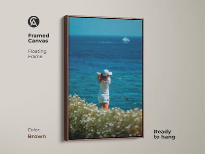Brown framed canvas art featuring a female golfer. This beautiful artwork captures a woman golfer in motion. The ocean is in the background. Ready to hang this framed canvas adds a touch of sophistication to your wall decor.