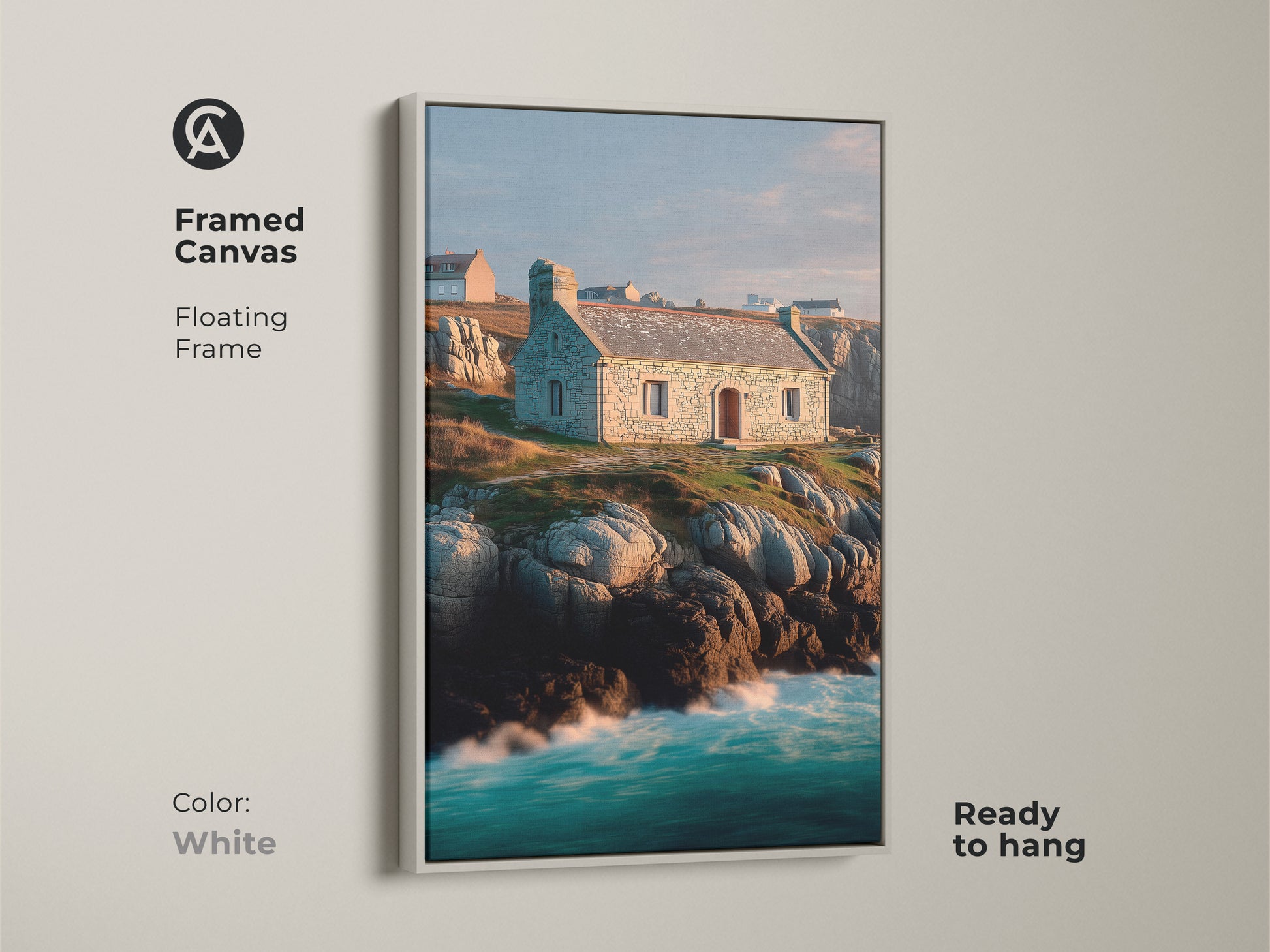 Framed canvas of a coastal stone cottage landscape. Floating frame in white finish highlights the art. Ocean waves and rocky coastline artwork create a peaceful atmosphere. Blue green teal colors add a touch of coastal charm. Ready to hang.