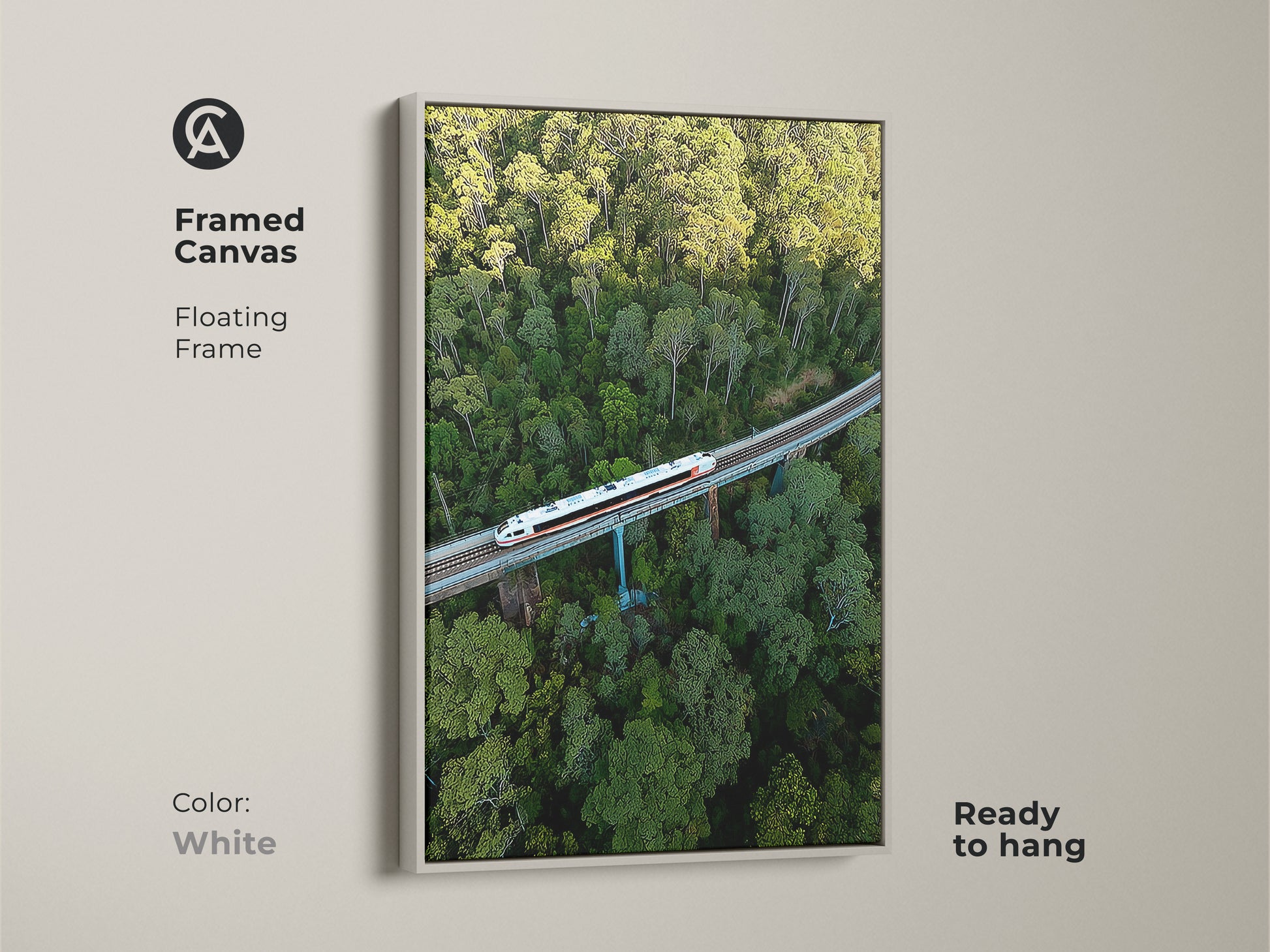 Framed canvas art presents an aerial train scene. A floating frame in white surrounds this green forest canvas. This modern transportation print is ready to hang. The nature landscape print provides unique wall decor. This train crossing forest artwork is captivating.
