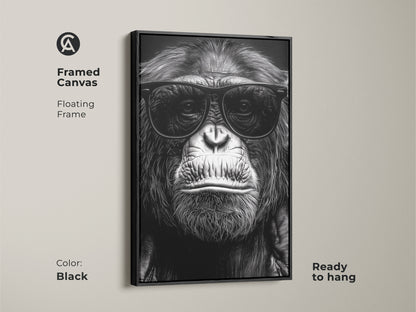 A framed canvas features a chimpanzee wearing sunglasses. The black floating frame enhances this monochrome gorilla art. It's ready to hang for study room or office wall decor. Perfect eclectic animal art for an animal lover gift. This primate portrait is a unique wall hanging.